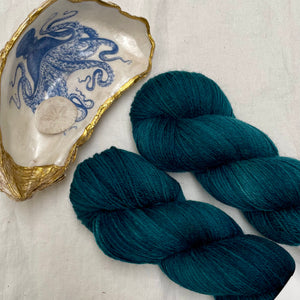 Deep teal sock yarn next to an octopus decal on an oyster shell
